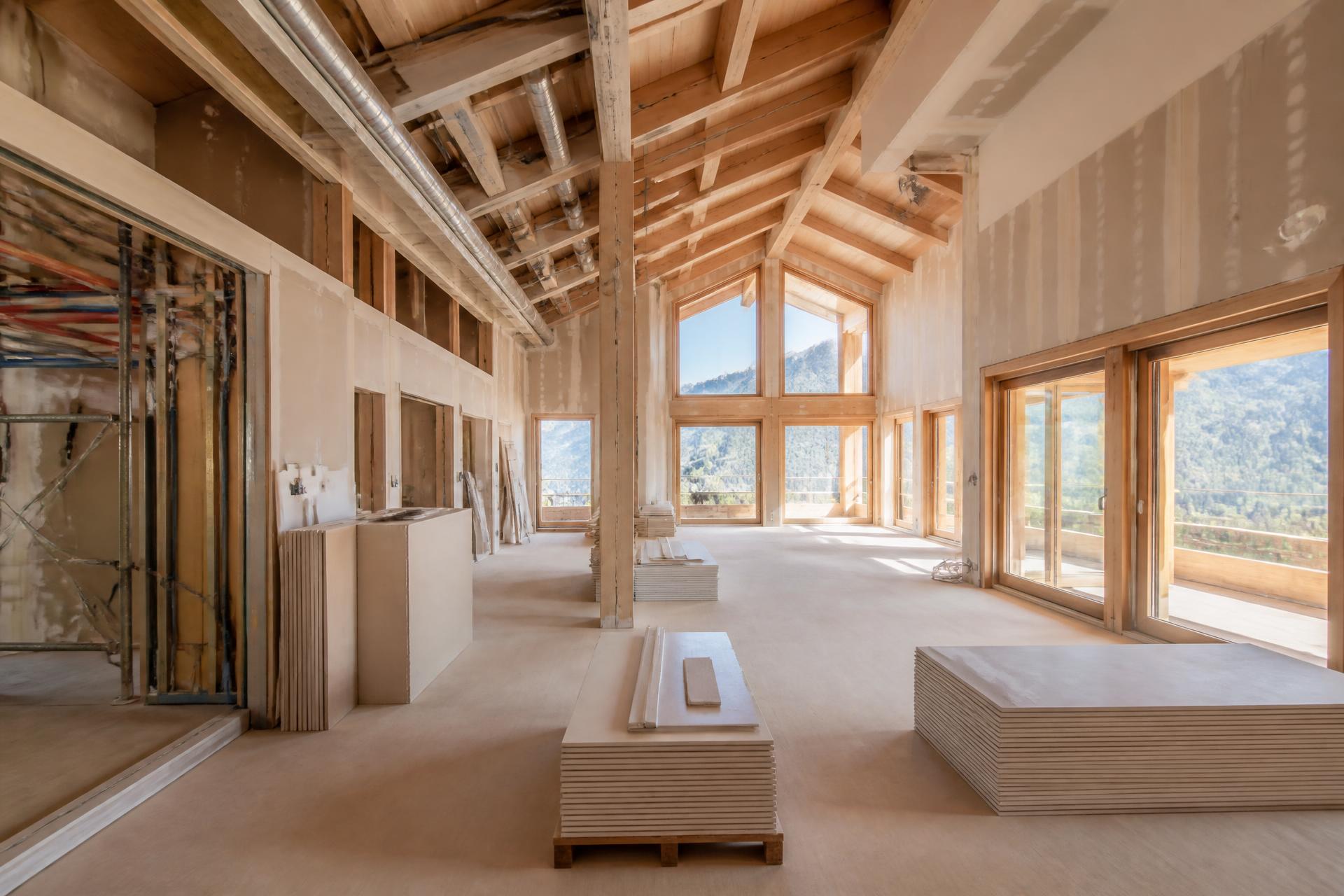 Interior de chalet en obra con tabiquería e instalaciones a la vista y materiales organizados